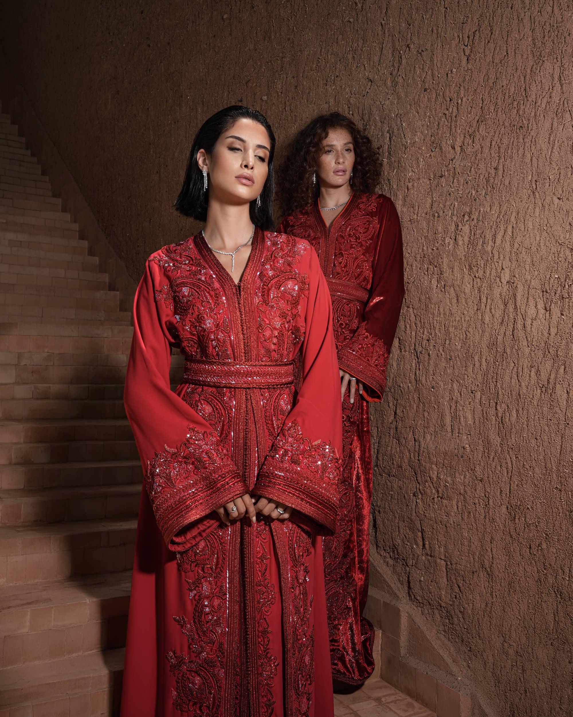 Carmine Cadence red crepe Moroccan kaftan with sequined paisley embroidery, braided belt and flared sleeves, shown alongside a second look