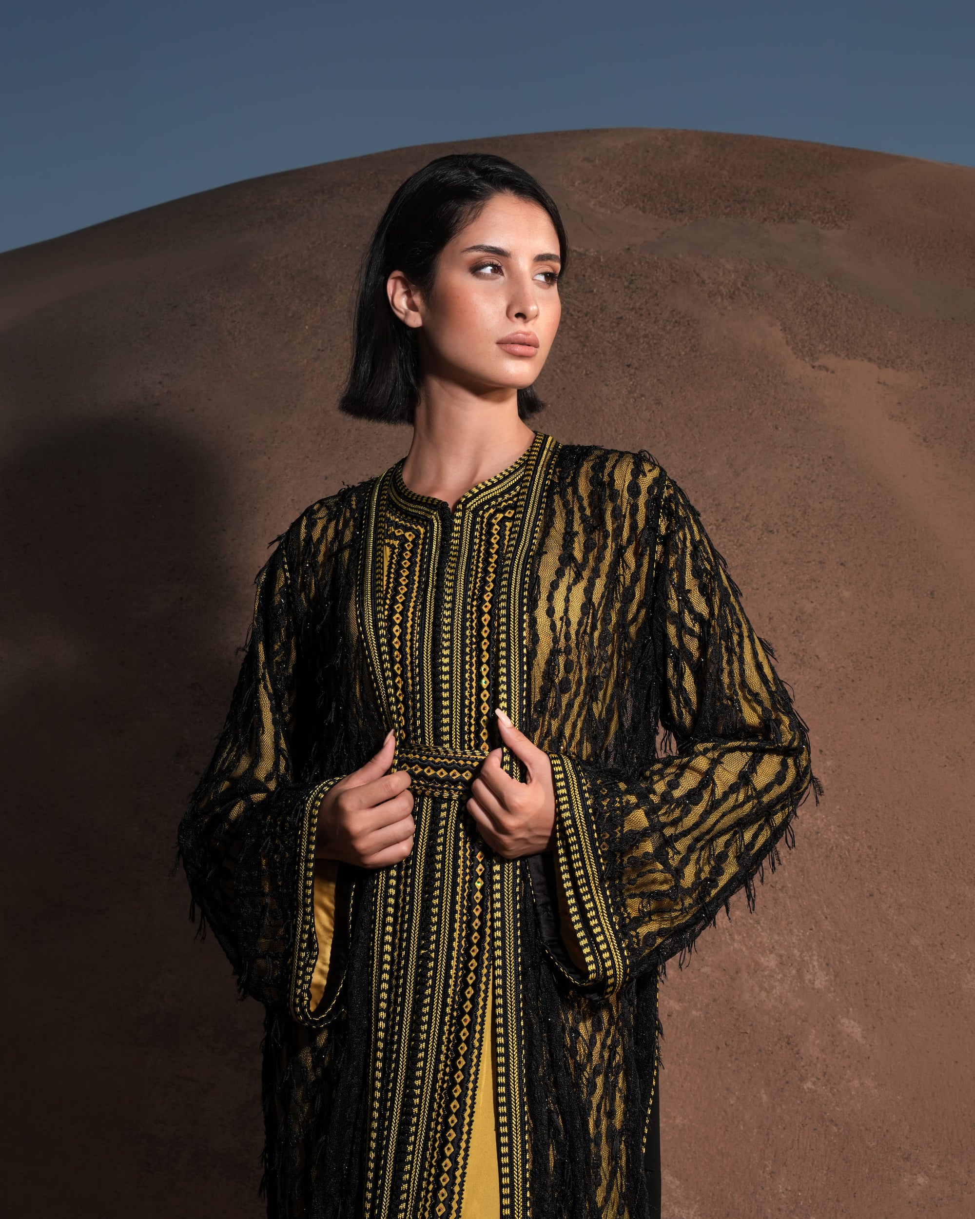 Onyx Serenade fringed black lace Moroccan kaftan over a mustard-gold dress