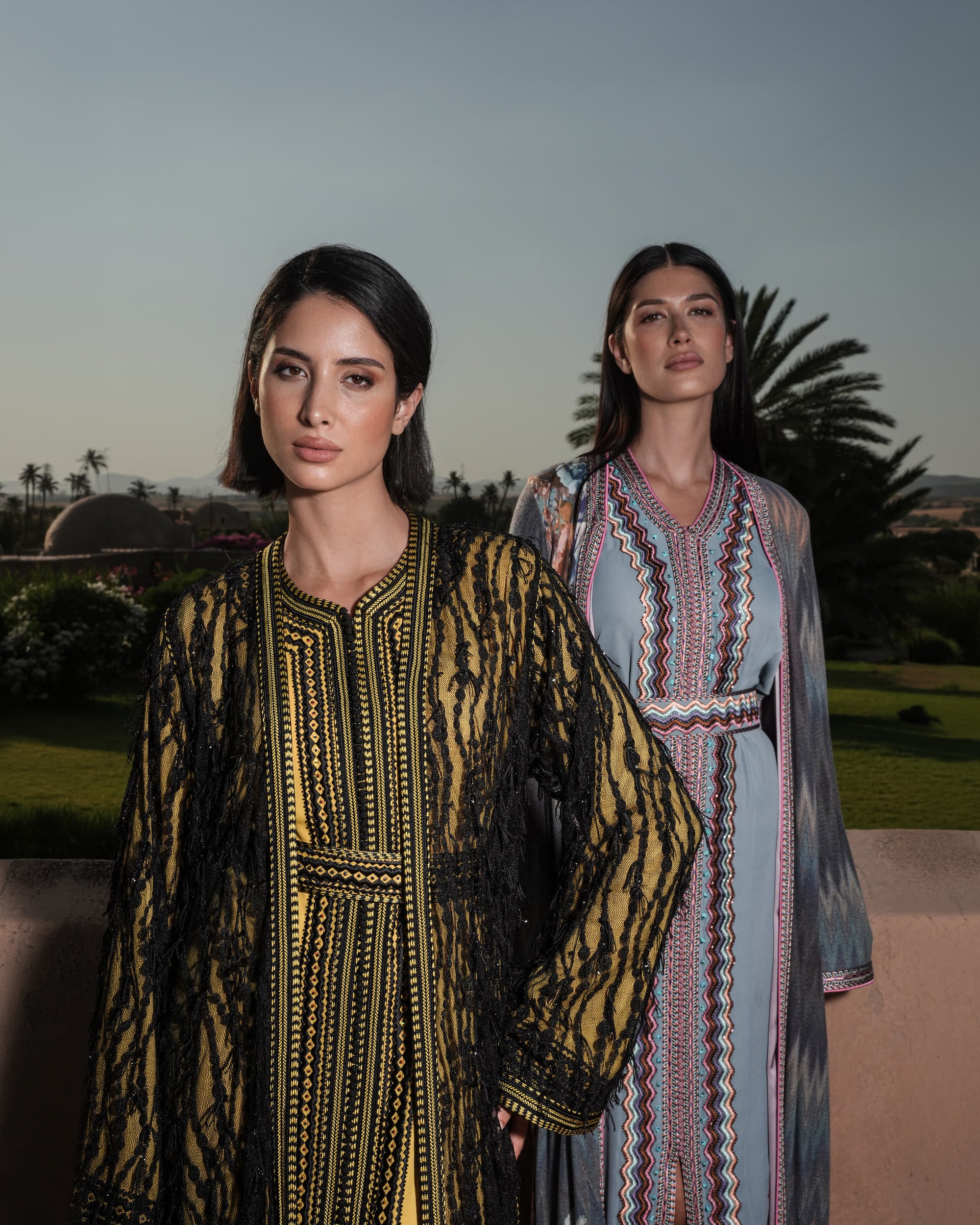 Onyx Serenade fringed black lace Moroccan kaftan over a mustard-gold dress, shown alongside a second look