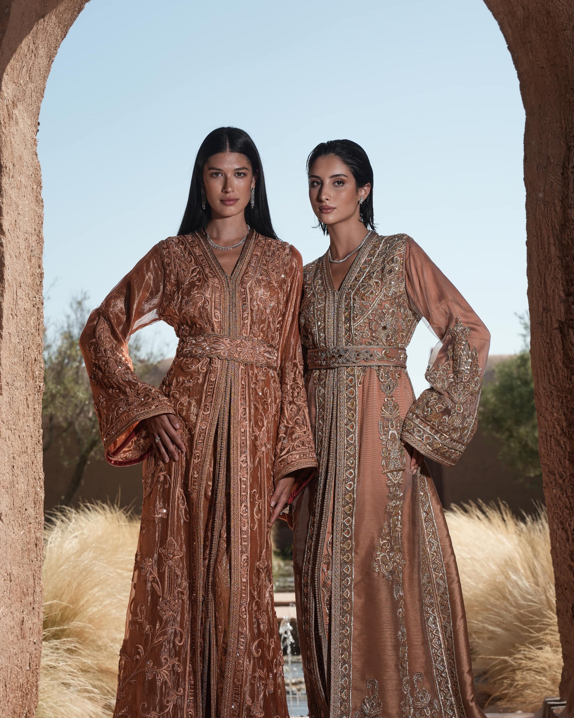 Rosewood Aurora copper-rose organza Moroccan kaftan with silver embroidery and jewelled belt, shown alongside a second look